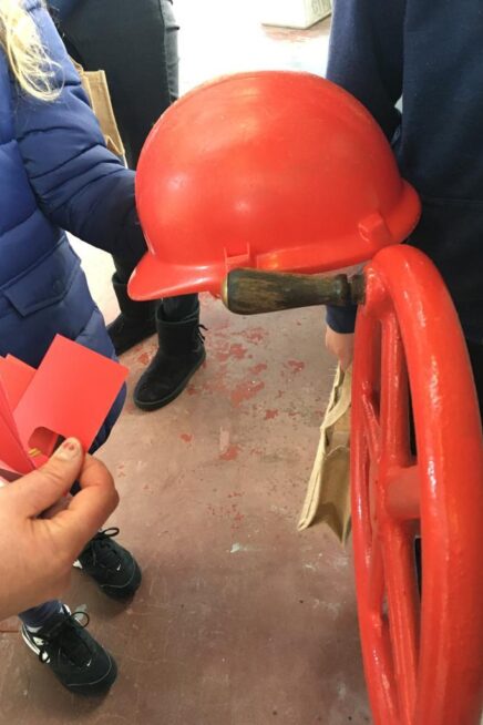 Hands holding two red cards up against a red hat and red wheel