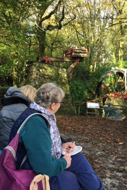 Two people sit outdoors with a paper sound map listening to sounds