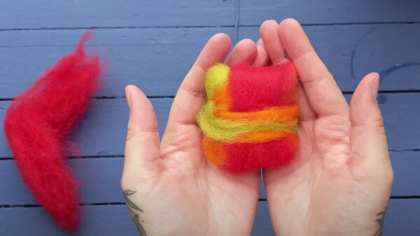 Hands with a felted soap bar inside them against a blue background