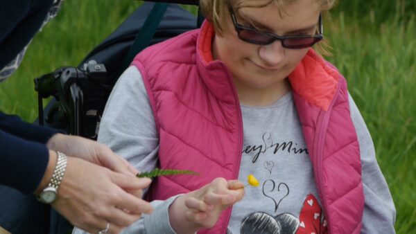 A young woman exploring the detail of a buttercup flower