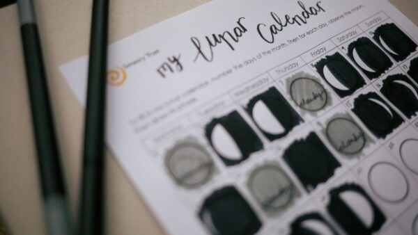 Lunar calendar partially completed with two pens in the foreground