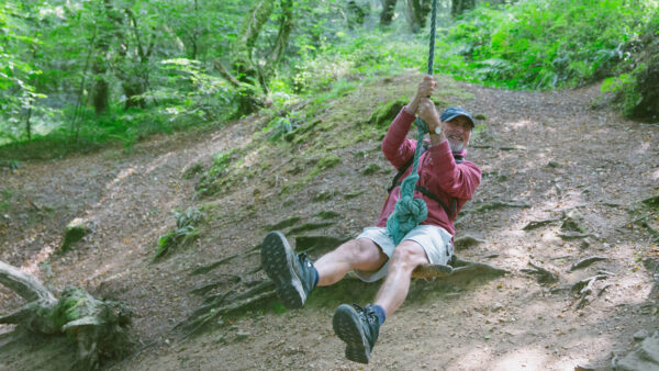 Smiling man on rope swing in the woods