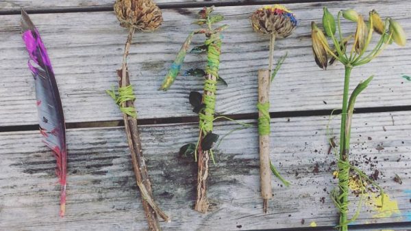 A selection of natural painting brushes made from twigs, feathers and seed heads bound with twine and dipped in paint