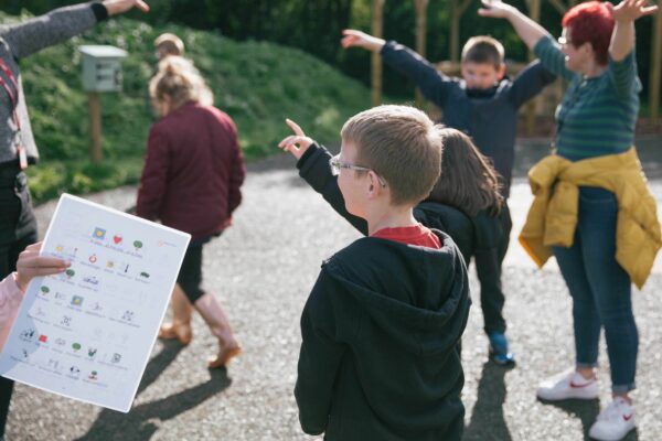 Widgit sheet in foreground with children and adults stretching their arms out