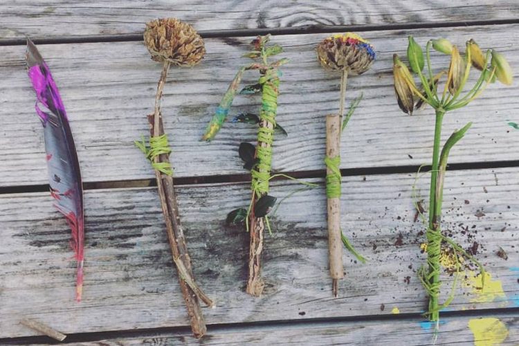 A selection of natural painting brushes made from twigs, feathers and seed heads bound with twine and dipped in paint