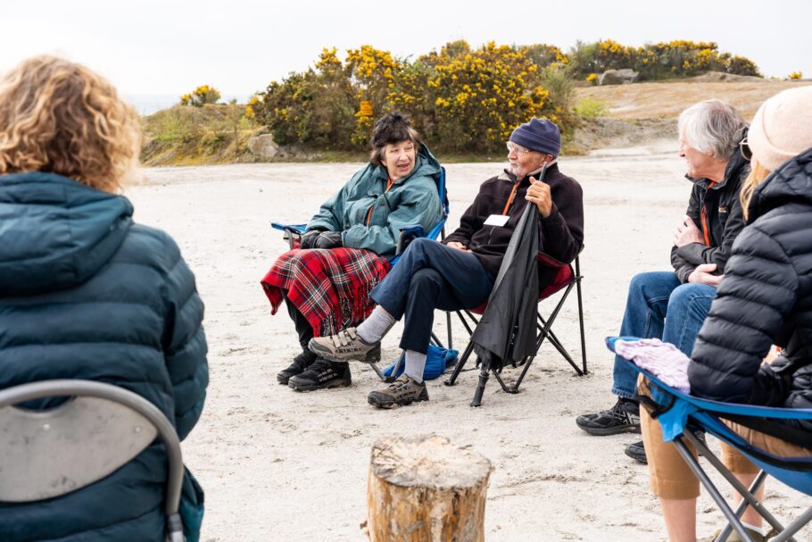 Participants of a dementia friendly walking group gather on camping chairs to talk