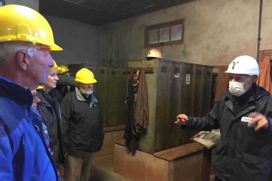 Person in white hard hat talks to a group of people inside a mine
