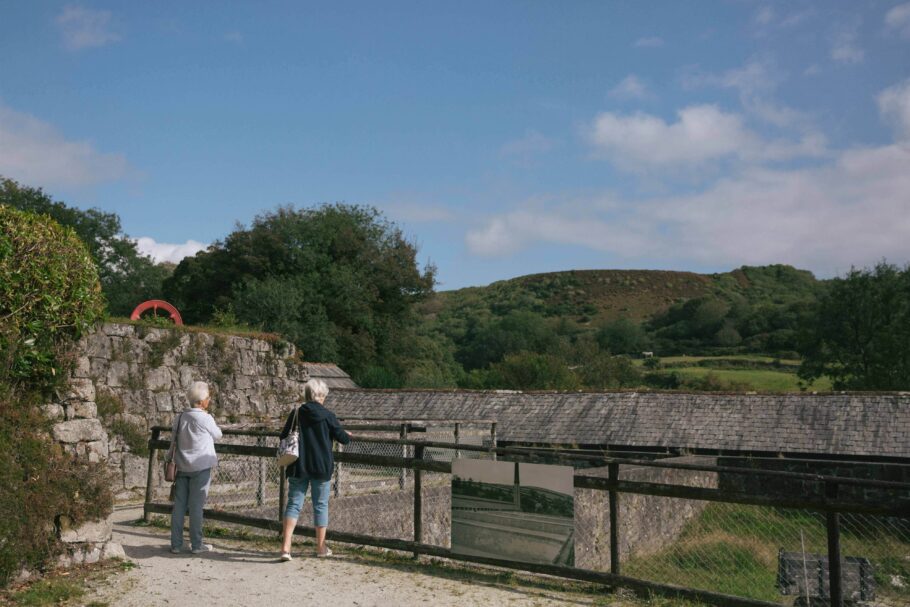 Two people have their backs to the camera looking at a clay drier at Wheal Martyn