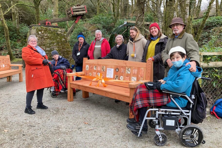 A group of people gather around an outdoor bench