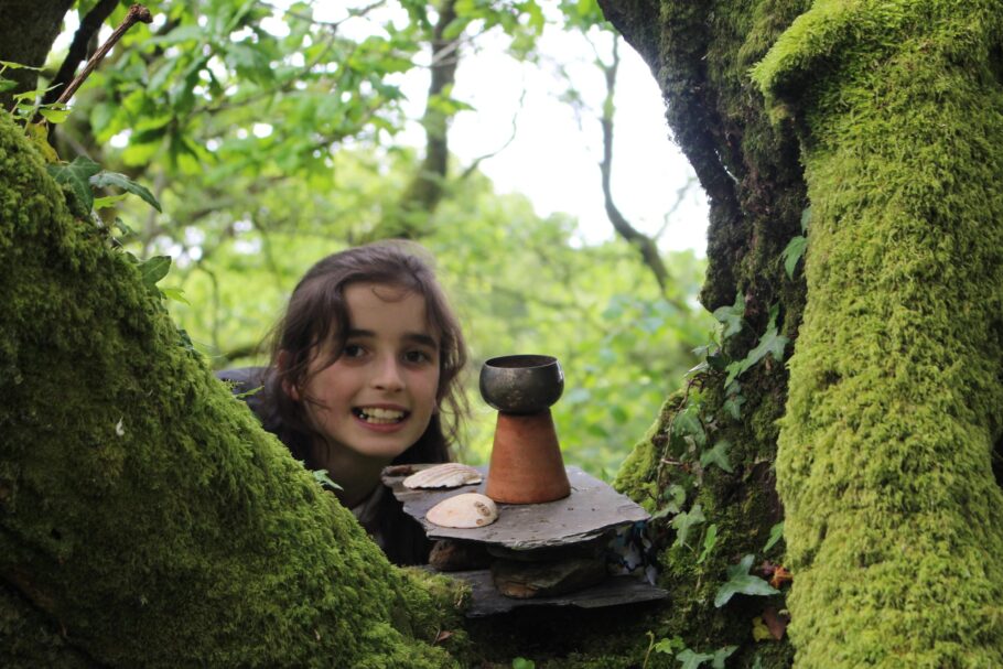 A girl looking through mossy branches of a tree